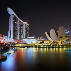 Stunning night view of Marina Bay Sands and Helix Bridge illuminated over water in Singapore.