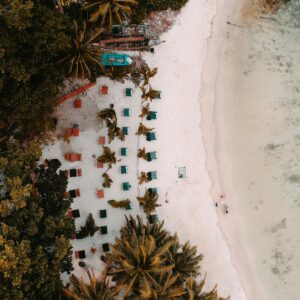 Aerial view of a tropical beach with sun loungers, palm trees, and white sand in the Andaman Islands.