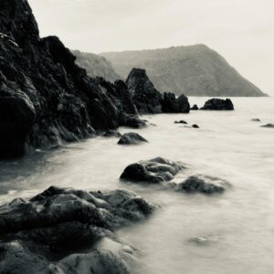 Dramatic monochrome view of rocky coastline at Arambol Beach, GA, India during the day. Captures serene ocean waves.