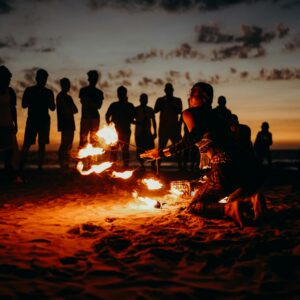 A mesmerizing fire performance on a beach at sunset with a captivated crowd in Goa.