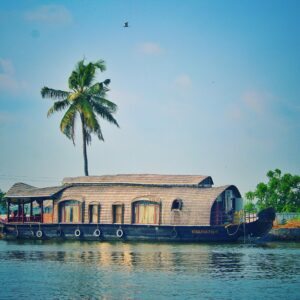 Picturesque view of river with green palms on bank and shabby wooden boathouse under blue sky in tropical countryside
